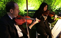 Two people playing the violin outside