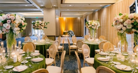 Reception room with dining tables topped with tall floral arrangements 