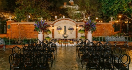 The Magnolia Park Terrace wedding venue with a fountain, floral arrangements, chairs and Haunted Mansion in the background