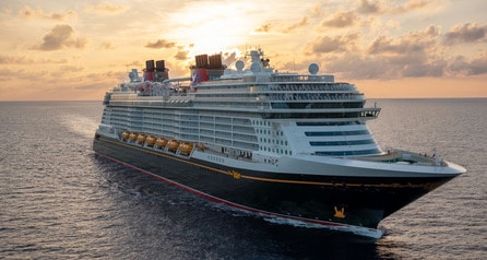 The Disney Wish ship sailing on calm waters at sunset