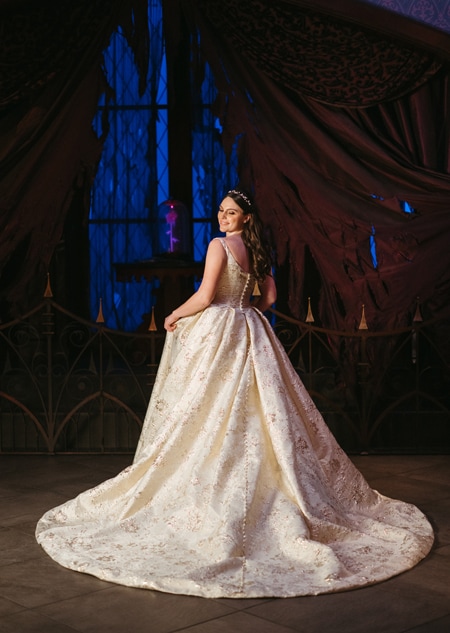 The back of a bride wearing a Disney Fairy Tale Weddings 35th Anniversary Collection Belle inspired wedding gown featuring embroidery, an A line silhouette and a train