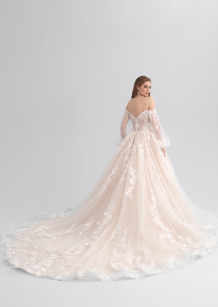 A woman looking over her shoulder wearing a lacy wedding dress with a long train