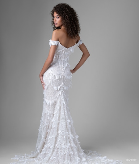 The back of a bride wearing a Tiana inspired sheath gown featuring off the shoulder sleeves, a train and light fringe detail