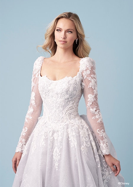 A bride wearing a Cinderella inspired A line wedding gown featuring embroidery, long lace sleeves and a semi sweetheart neckline