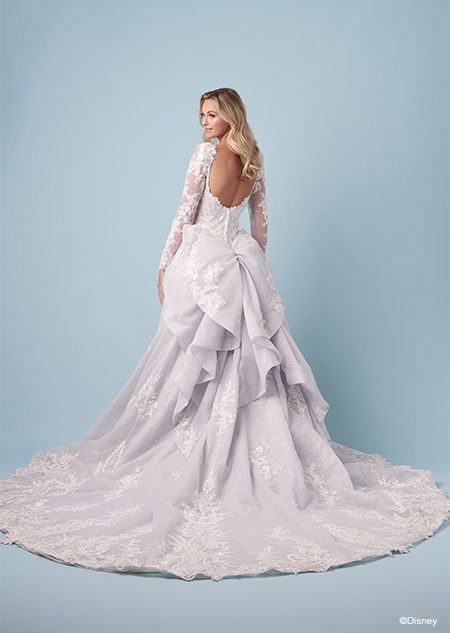 The back of a bride wearing a Cinderella inspired A line wedding gown featuring embroidery, long lace sleeves and a gathered bustle
