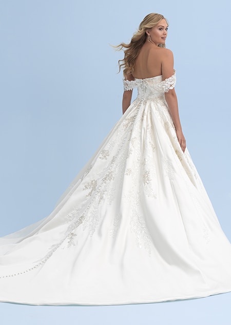 The back view of a woman in a wedding dress with straps that cross just above her elbows and a skirt with a full train