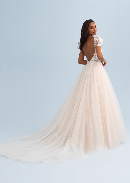 A woman looking over her shoulder wearing a wedding dress with a tulle skirt and train