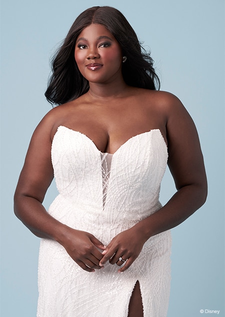 A bride wearing a strapless Ariel inspired sheath gown featuring an illusion neckline and a high slit