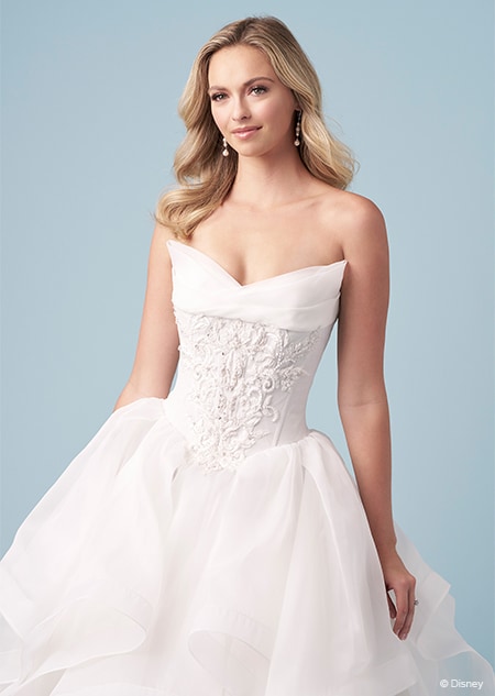 A bride wearing a strapless Cinderella inspired ball gown featuring an embroidered bodice and a shallow V neckline