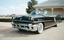 A classic convertible car with chrome details and white wall tires 