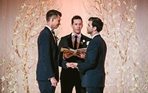 Two men getting married near small lit trees