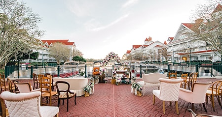 An outdoor wedding ceremony setup with mixed seating, floral arrangements and a decorated archway near a water view