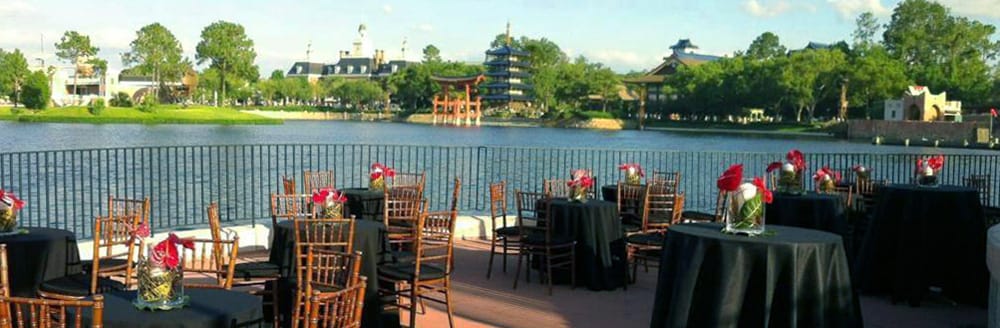 Small round tables arranged near the water with views of World Showcase