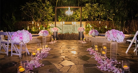 A wedding aisle with candles and rose petals at Kula Wai Outdoor Hydrotherapy Garden