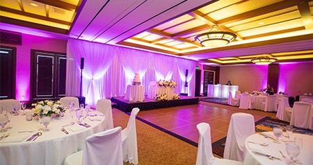 Several round tables, a small dance floor and a cake table in the Kaʻala Ballroom at Aulani, A Disney Resort & Spa