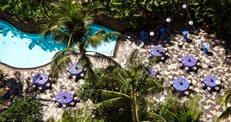 An outdoor wedding reception space next to Wailana Pool, surrounded by palm trees at Aulani, a Disney Resort & Spa