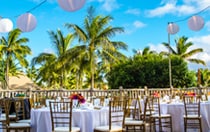 On a patio, paper lanterns are strung above tables set with floral centerpieces
