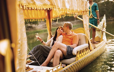 A man and a woman take a ride in a boat along a river in Asia