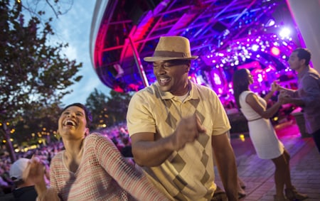 A woman and a man show off their dance moves at an outdoor music venue 
