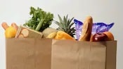 アラスカ リンゴ、セロリ、バゲットなどの食べ物が見える食料品の袋 2 つ