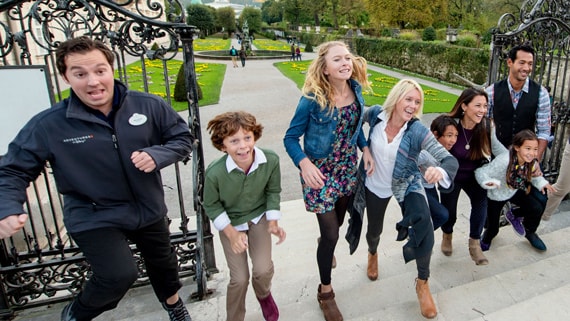 Travelers walking up a flight of steps with an Adventures by Disney Guide