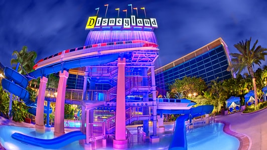 An outdoor pool and waterslide of Disneyland Hotel at nighttime