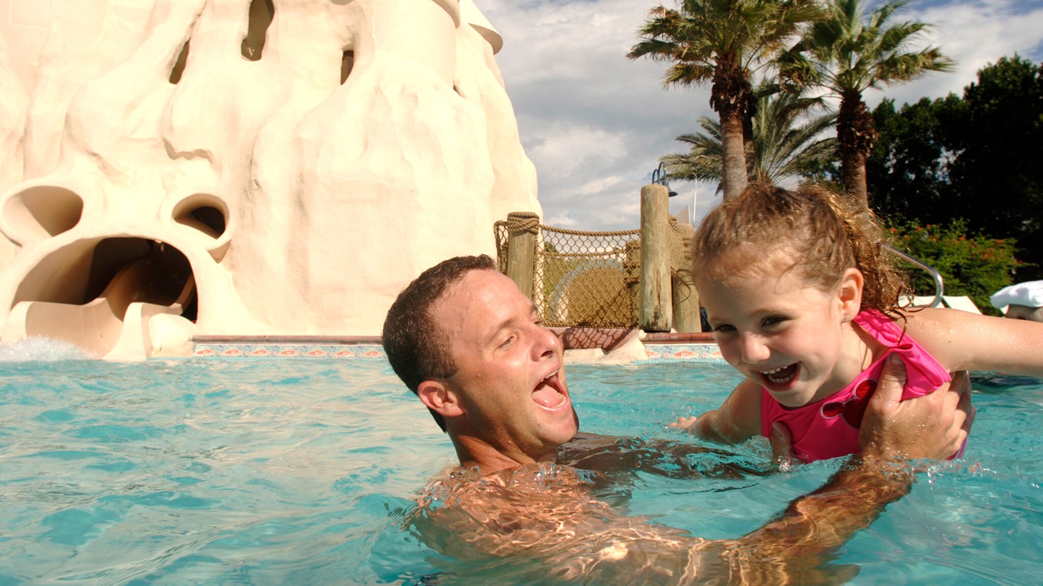 A father and young daughter playing in a Resort pool