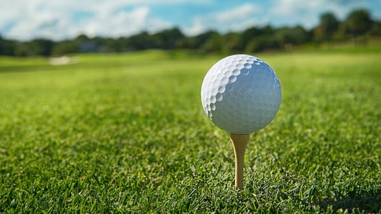 A golf ball atop a tee on an open fairway