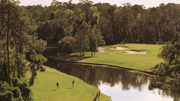 A lush golf course with a large water hazard and several sand traps