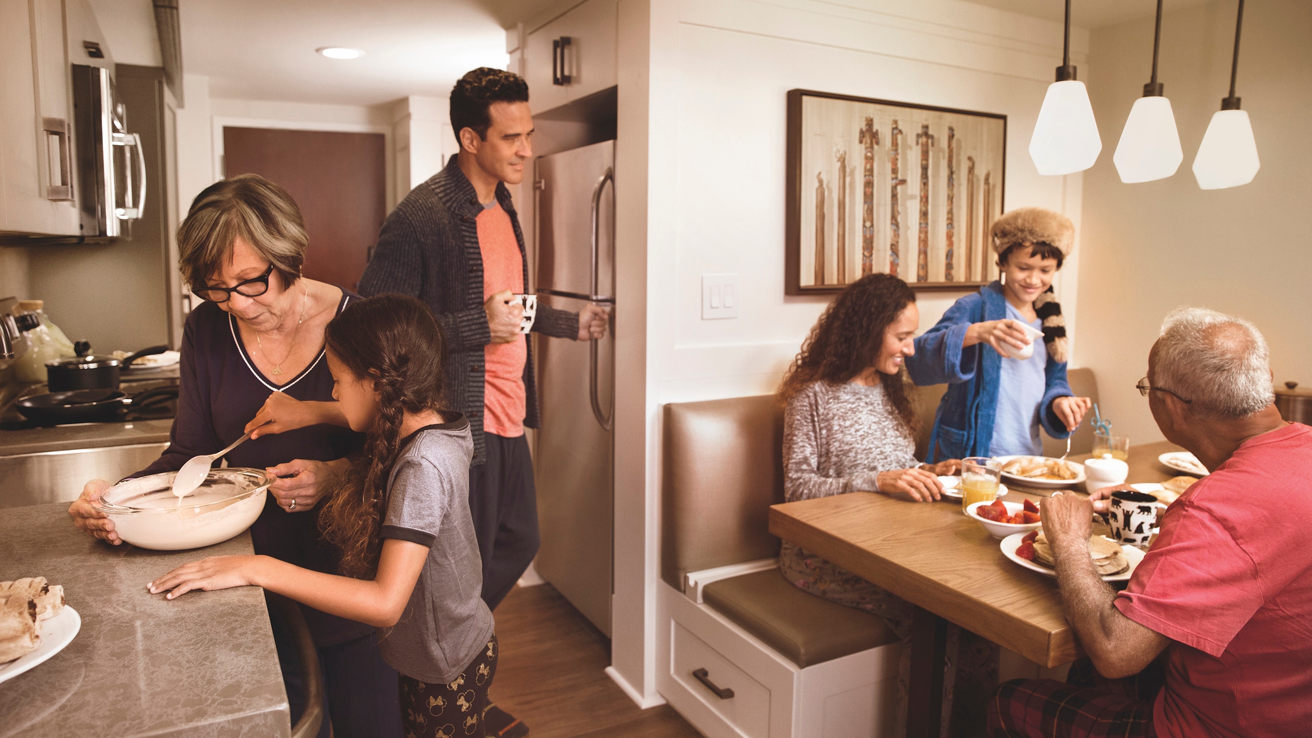 A family of 6 gathered for a meal in the kitchen and dining area of their Resort villa