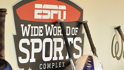 Cuatro bates de béisbol junto a un letrero que lee "ESPN Wide World of Sports Complex"