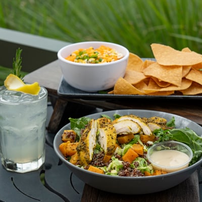 A table set with a salad, vegetables, snacks and a lemon drink