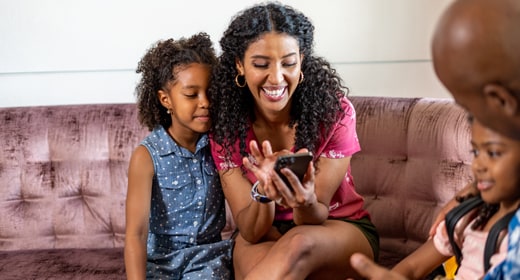 A family smiling together while looking at a smartphone screen