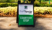 A sign on a sidewalk with text that reads ′Tramsporter, presented by Enterprise, Courtesy Stop′