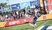 A football player catches a ball on a field in front of many spectators