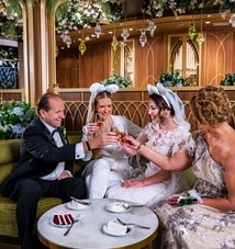 A group of 4 Guests in wedding attire enjoying beverages and smiling at each other at The Bayou