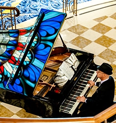 A man playing a grand piano in a Disney Cruise Line ship atrium for a wedding ceremony